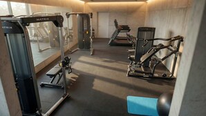A gym with cardio machines, weight training equipment, and a blue mat. - BASE Achensee Balance N°01 – Garden (Achenkirch)
