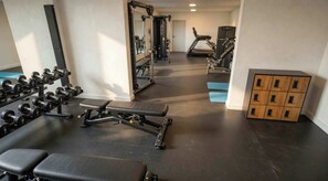 Un gimnasio con equipo de ejercicio, bancos y un módulo de almacenamiento.