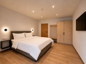 A modern bedroom with a bed, bedside tables, a wardrobe, and a wall-mounted TV. - BASE Achensee Balance N°02 (Achenkirch)