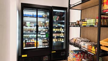 A refrigerated display case with various food items and a shelf with packaged goods.