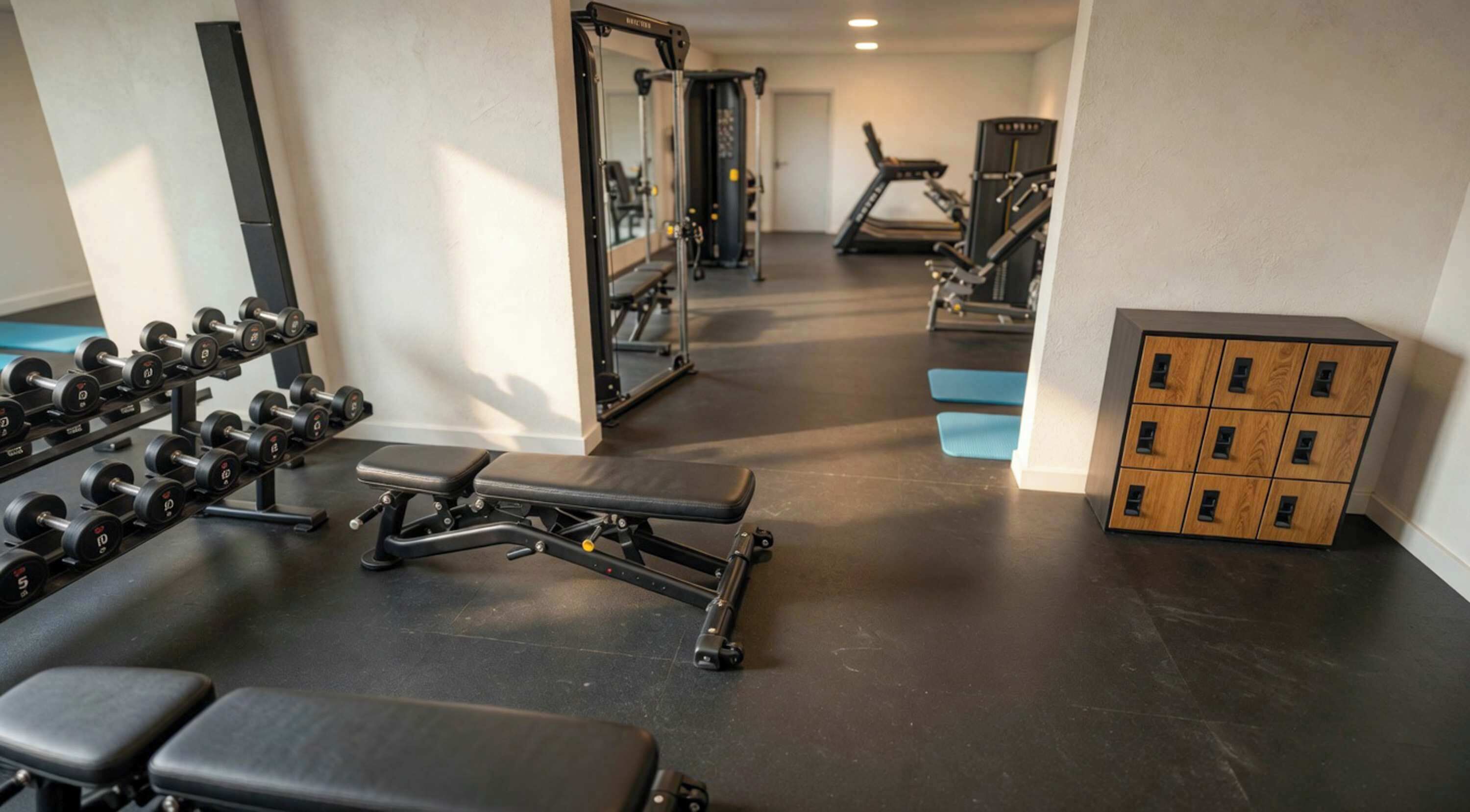 A gym with exercise equipment, benches, and a storage unit.