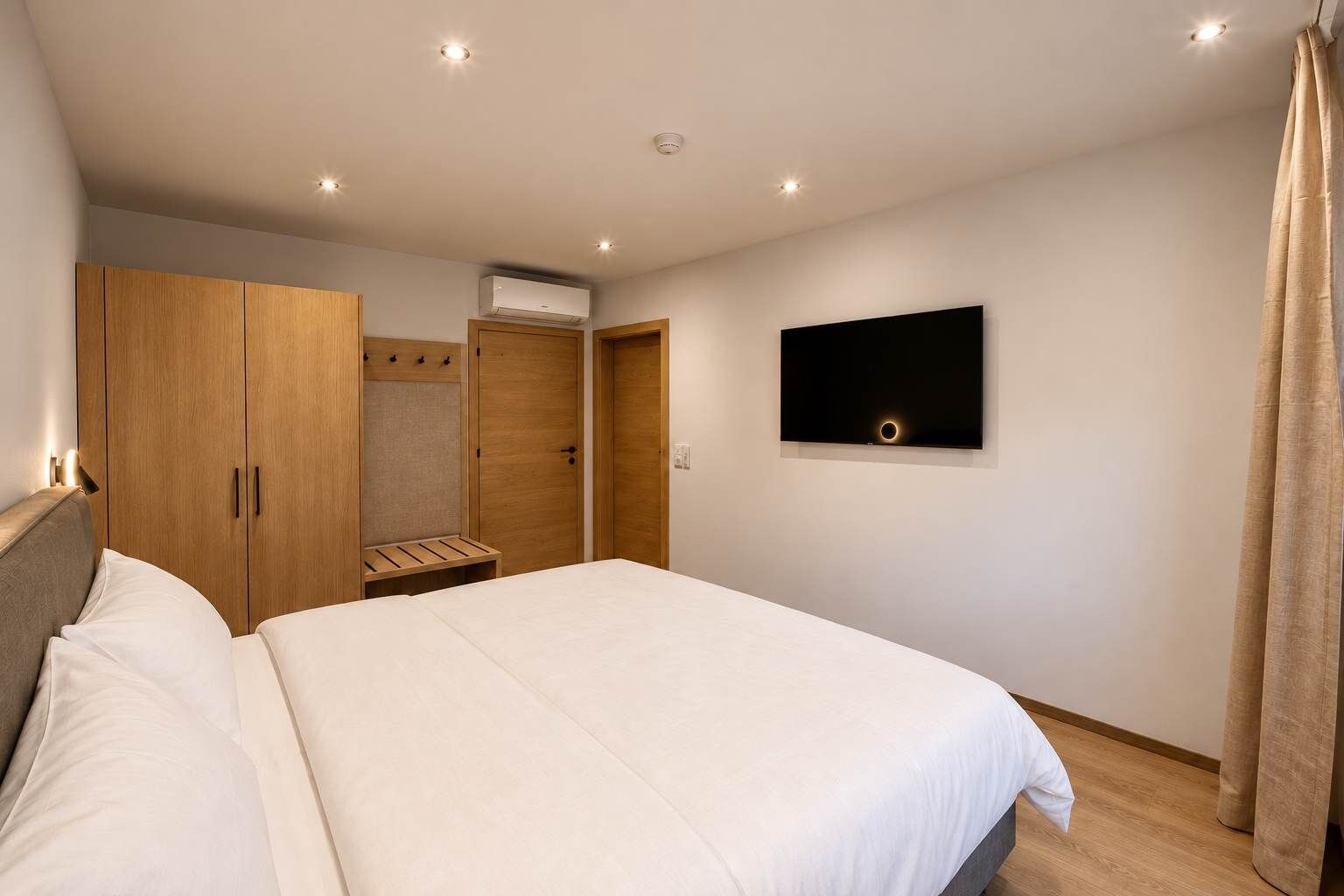 Un dormitorio con cama, armario, televisor y aire acondicionado.