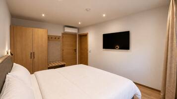 Un dormitorio con cama, armario, televisor y aire acondicionado.