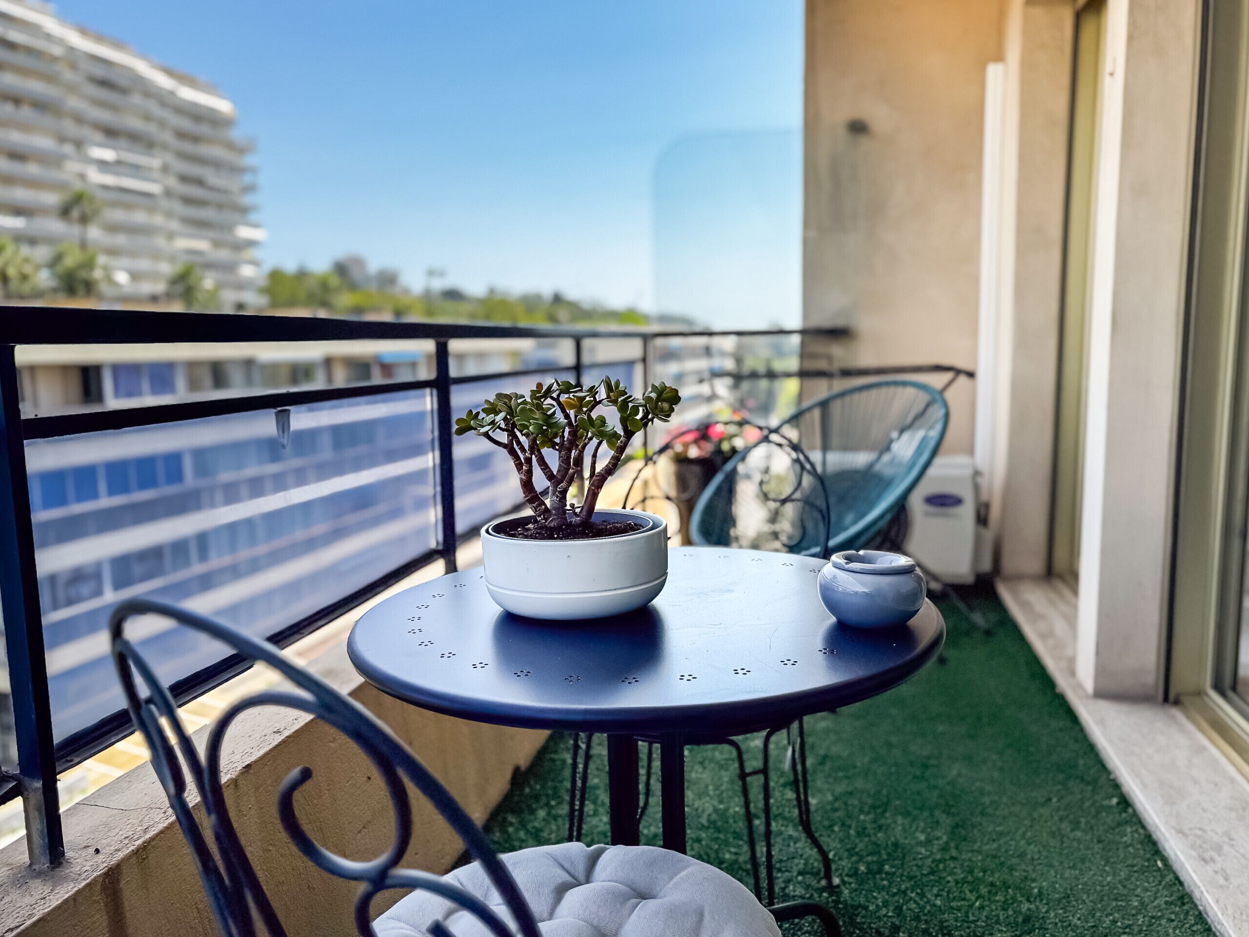 Un balcon avec un pot de fleurs, une petite table et une chaise.