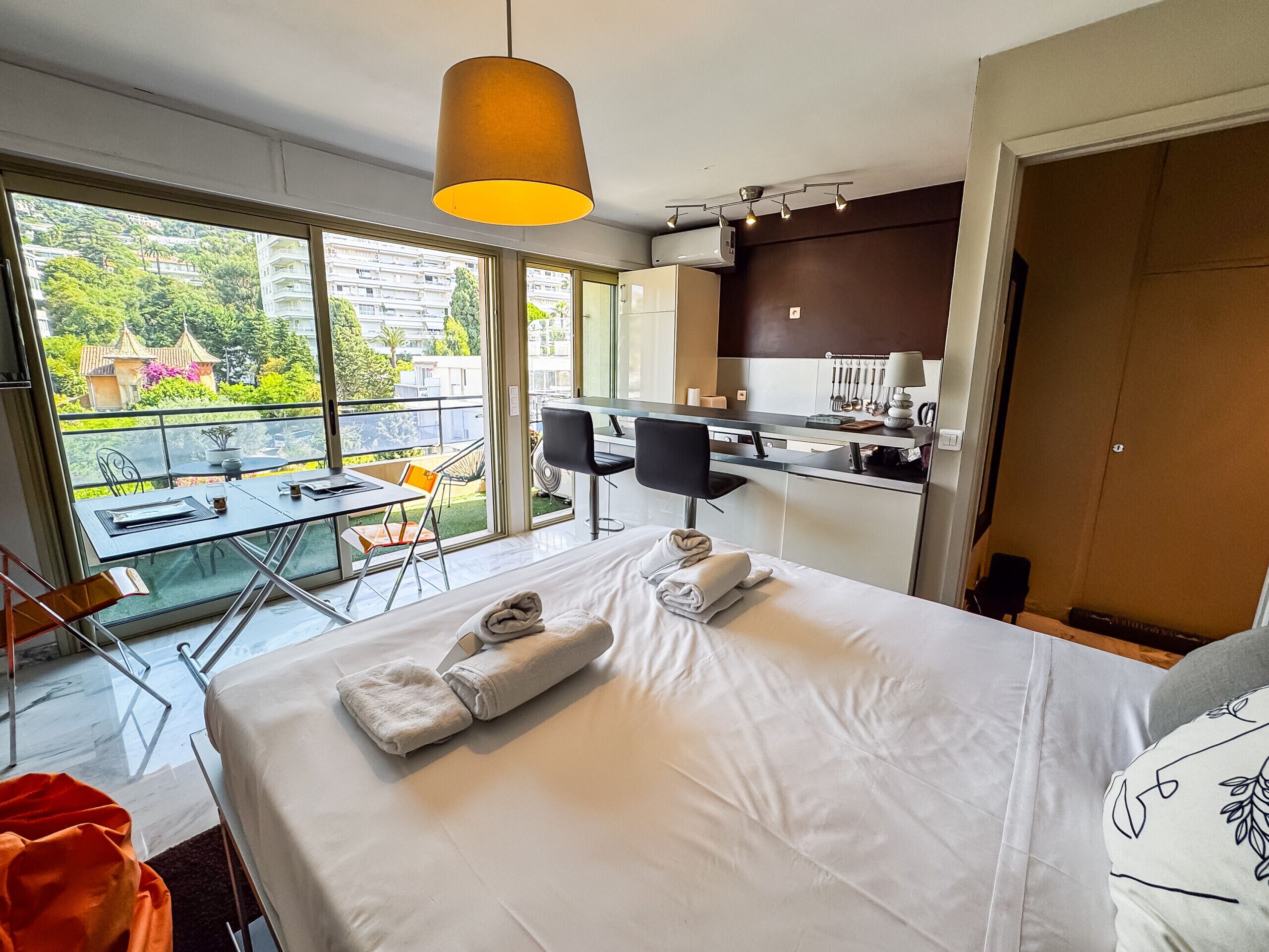 Et hotelværelse med seng, skrivebord, stol, en balkon med udsigt og et tekøkken.