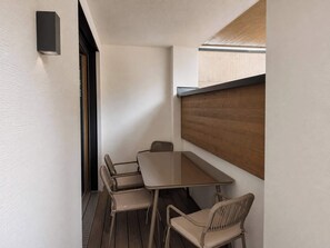 A small, enclosed outdoor dining area with a table and four chairs, a wooden slat wall, and a light fixture on the wall. - BASE Achensee Balance N°07 (Achenkirch)