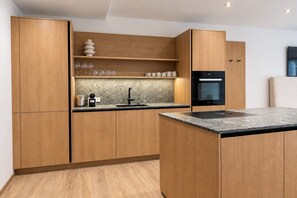 Eine moderne Küche mit Holzausstattung, einem Einbauofen und einer Arbeitsplatte aus Granit.