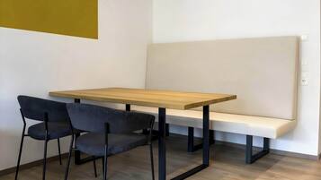 Una habitación con una mesa de madera, dos sillas, un banco y una pared de color claro.