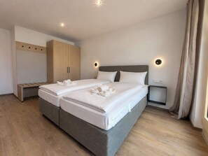 A double bed with pillows and towels, a wooden wardrobe, a bedside table, and a nightstand. - BASE Achensee Freedom N°17 (Achenkirch)