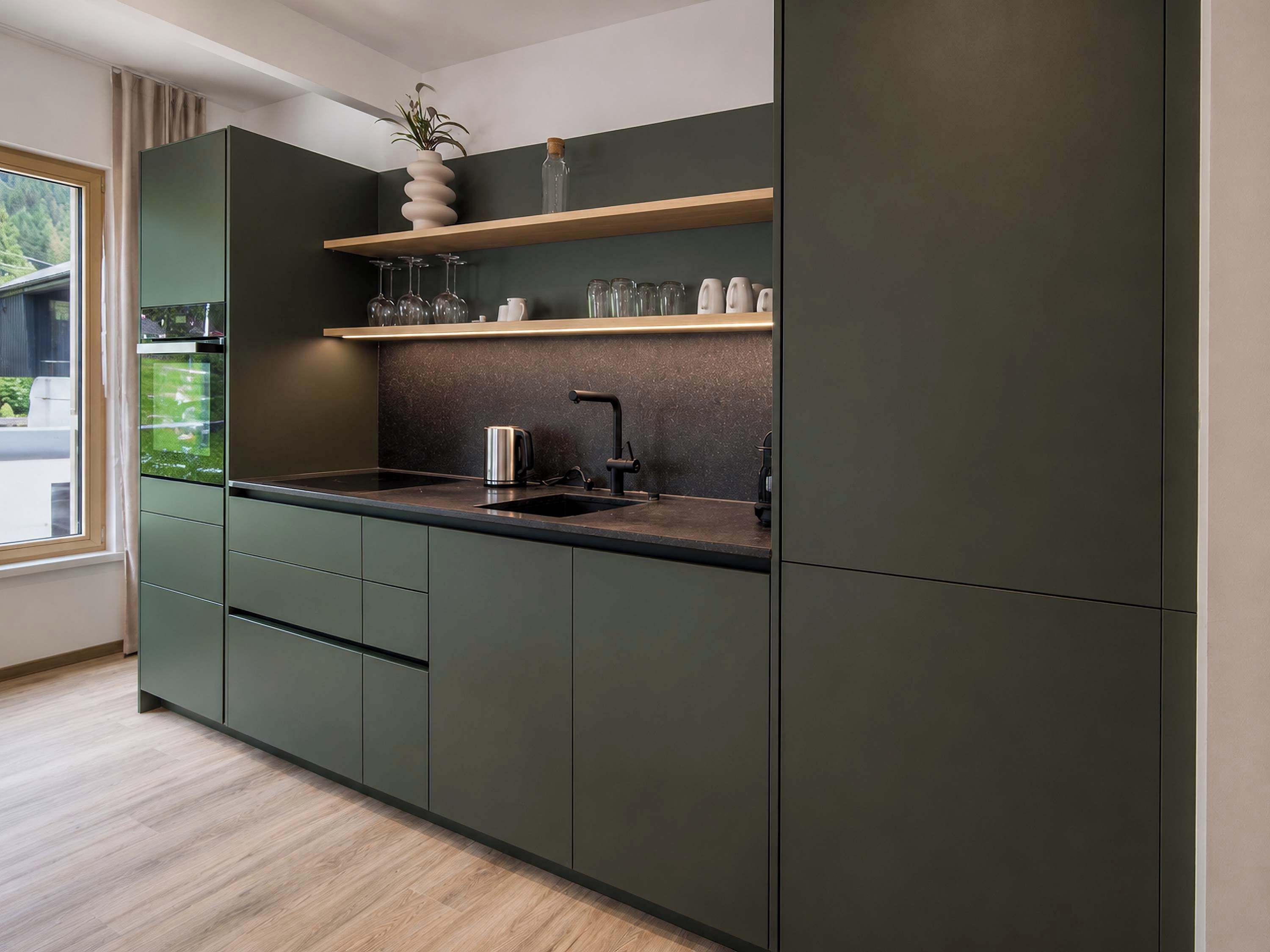 Eine moderne Küche mit dunklen Schränken, einer Holz Arbeitsplatte und einer eingebauten Ablagefläche mit Gläsern und einer Pflanze.