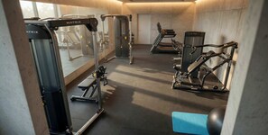 Ein Fitnessraum mit Cardiogeräten, Krafttrainingsgeräten und einer blauen Matte.