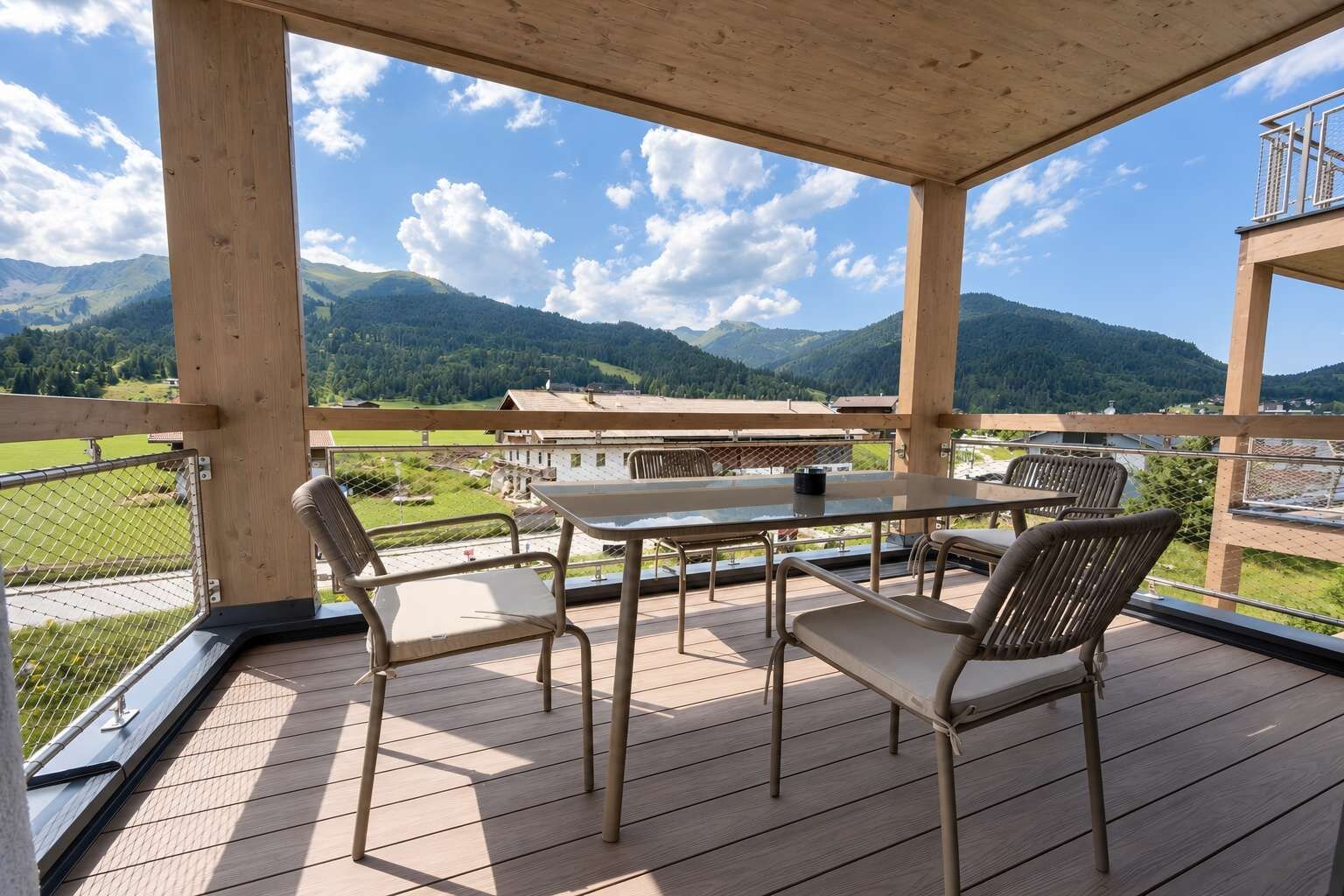 Eine Holzterrasse mit Tisch und Stühlen mit Blick auf eine gebirgige Landschaft.