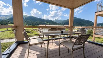 Eine Holzterrasse mit Tisch und Stühlen mit Blick auf eine gebirgige Landschaft.