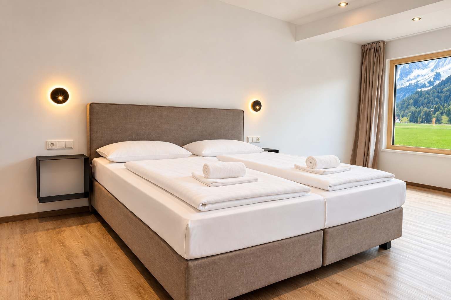 Ein Doppelbett mit zwei Kissen, ein Nachttisch und ein Fenster mit Blick auf eine grüne Landschaft.
