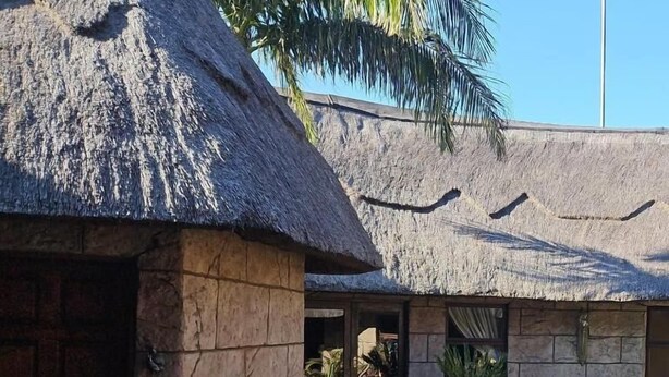 A building with a thatched roof, stone walls, and potted plants.