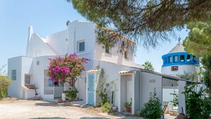 A white building with a blue tower, surrounded by potted plants and a cobblestone path. - Studio with a garden terrace (Albufeira)