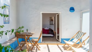 Una habitación con una cama, una mesa de madera y dos sillones a rayas.