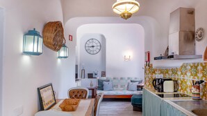 A compact kitchen with a dining area, a clock, and a hanging basket. - Apartment with a terrace and a view of the garden (Albufeira)