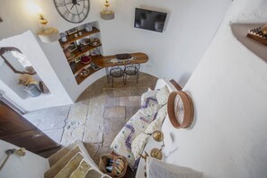 A room with a bed, a wooden table with chairs, a TV, and a clock on the wall. - Historic Windmill – Panoramic Views (Albufeira)
