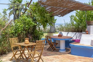 Un patio al aire libre con mobiliario de madera, una mesa y una pared azul y blanca.