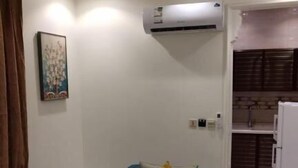 Una sala de estar con sofá, una mesa de centro, un equipo de aire acondicionado y una cocina al fondo.