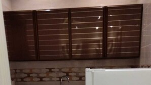 Una cocina compacta con alacenas marrón oscuro, un refrigerador blanco y un salpicadero de azulejos.