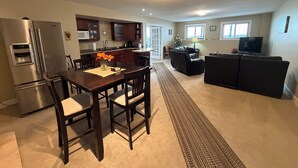 A modern kitchen with a refrigerator, microwave, and dining area with chairs and a table. - Poolside Oasis in Penticton | Private Fenced Pool, 3BR Family Retreat (Penticton)