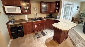 A kitchen with wooden cabinets, a microwave, a sink, a toaster, and a coffee maker. - Poolside Oasis in Penticton | Private Fenced Pool, 3BR Family Retreat (Penticton)