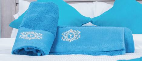 A neatly made bed with blue towels and pillows, a white bedspread, and a wooden headboard.
