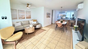 Ein modernes Wohnzimmer mit Sofa, Couchtisch und Essbereich mit Stühlen.