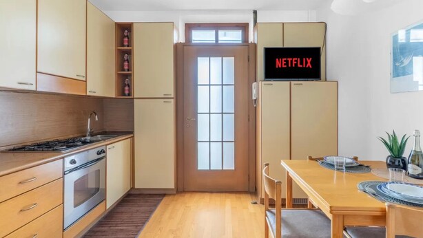 Una cocina moderna con horno empotrado, una mesa de comedor con sillas y una puerta con ventana.