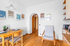 A dining area with a wooden table and chairs, a white armchair, and a hallway with an archway. - CA2 [Loreto - Cathedral] • 10 minutes from the Duomo • (Milano)