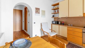 Una cocina compacta con muebles de madera, un microondas y una silla.