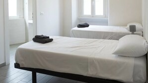 Un dormitori amb dos llits, una finestra i una porta.