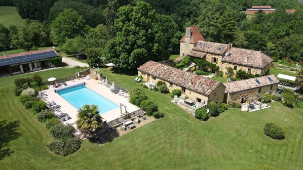 An aerial view of a property with a swimming pool, stone buildings, and lush greenery. - Vrbo Property (Saint-Pompon)