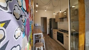 Eine moderne Küche mit einer Holzausziehtafel, Edelstahlgeräten und einem farbenfrohen Wandgemälde.