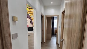 Ein Flur mit Holztüren, gefliestem Boden und einer Mikrowelle im Hintergrund.