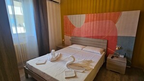 Ein Hotelzimmer mit einem Bett, einem Nachttisch, einer Wandleuchte und einem großen abstrakten Gemälde.