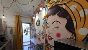 A modern kitchen with a microwave, a dining area with stools, and a vibrant mural on the wall.
