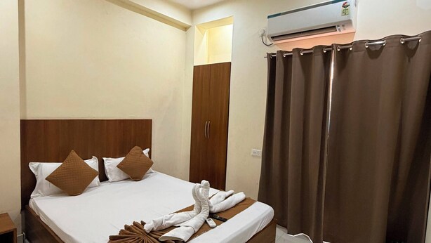 Habitación de hotel con cama, ventilador de techo, equipo de aire acondicionado, armario y cortina.