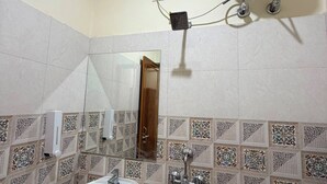 Un baño con lavamanos, espejo, ducha y calentador de agua instalado en la pared.