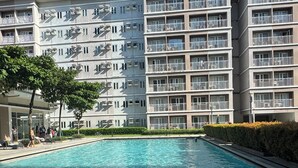 Un immeuble d’appartements moderne doté d’une piscine, de balcons et surplombant un ciel d’un bleu éclatant.