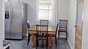 A dining area with a table and chairs, a refrigerator, a window with curtains, and a door. - Fantastic 3-bedroom house charming Hays (Hays)