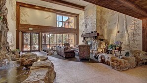 A spacious interior with a stone fireplace, large windows, and a view of the outdoors. - 1 Minute Walk to the Gondola/Shared Pool and Hot Tub/Private Patio (Keystone)