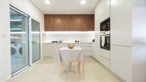 A modern kitchen with a dining table, wooden cabinets, and a built-in oven.