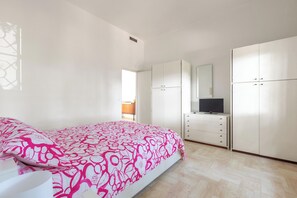 Ein Schlafzimmer mit Bett, Schminktisch, Fernseher und Kleiderschrank.