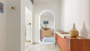 A hallway leading to a bedroom with a bed, a dresser, and a vase on a table. - Villa Sole e Mare by BarbarHouse (Polignano a Mare)