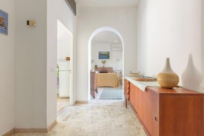 A hallway leading to a bedroom with a bed, a dresser, and a vase on a table. - Villa Sole e Mare by BarbarHouse (Polignano a Mare)