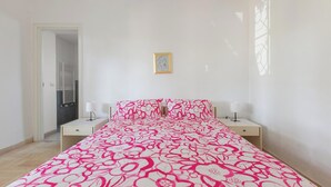 A bedroom with a bed, two bedside tables, a nightstand, a door, and a window. - Villa Sole e Mare by BarbarHouse (Polignano a Mare)