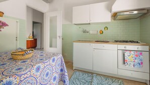 A compact kitchen with white cabinets, a stove, and a sink. - Villa Sole e Mare by BarbarHouse (Polignano a Mare)